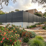 Garden with flowers and steps leading to a house with a fence